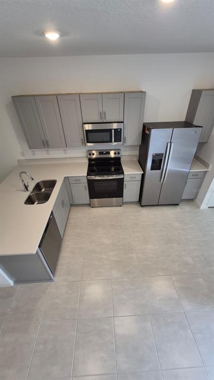 A modern kitchen features gray cabinets, stainless steel appliances, and light-colored countertops — 2860 SKYLINE LOOP, KISSIMMEE, FL