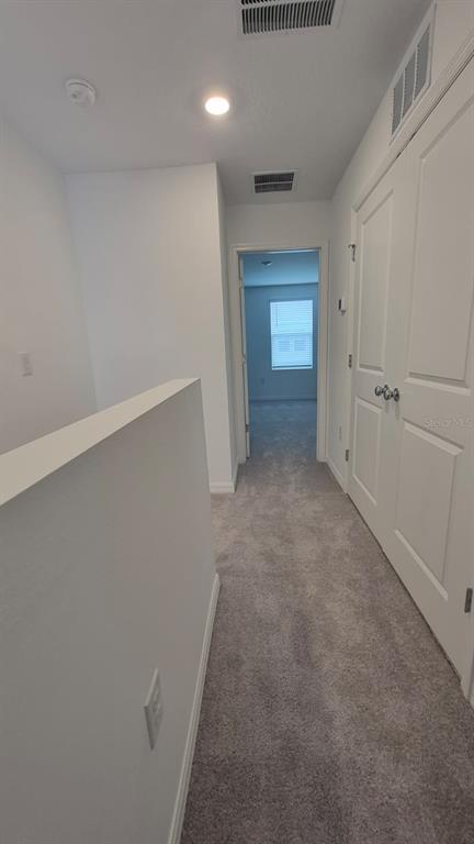 A carpeted hallway leads to a doorway with a view into a bedroom — 2860 SKYLINE LOOP, KISSIMMEE, FL