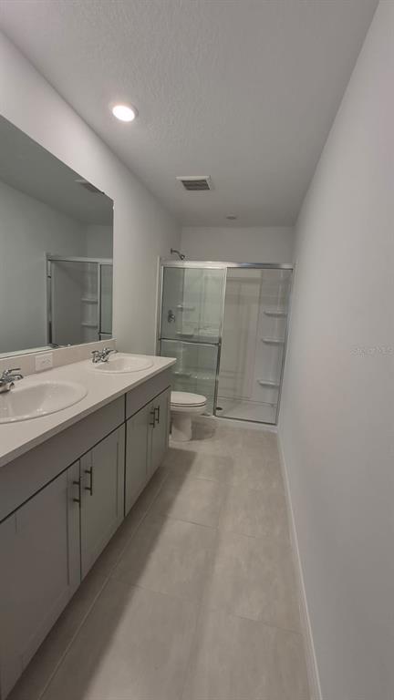 A bathroom features a double vanity with gray cabinets, a walk-in shower, and tile flooring — 2860 SKYLINE LOOP, KISSIMMEE, FL