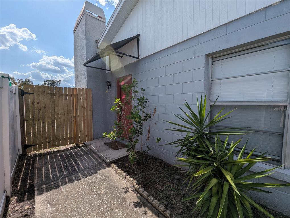 A concrete block exterior wall features a red door, a small awning, and a window — 1209 MOHRLAKE DRIVE, BRANDON, FL