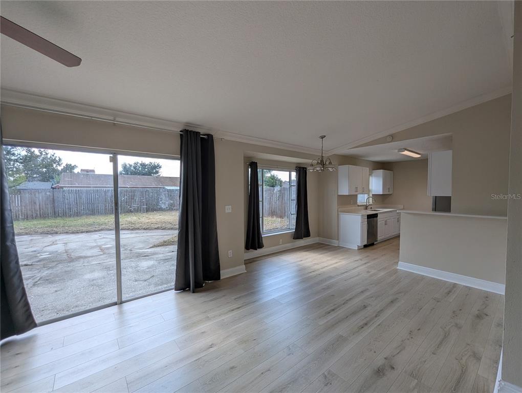 An open-concept living and dining area features light wood-look flooring and a sliding glass door — 1209 MOHRLAKE DRIVE, BRANDON, FL