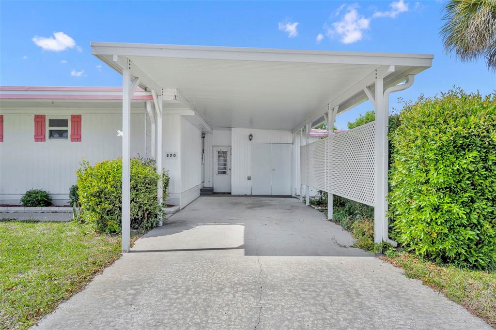 A white mobile home features a concrete driveway leading to a covered carport and entrance — 270 PALAI AVENUE, LEESBURG, FL