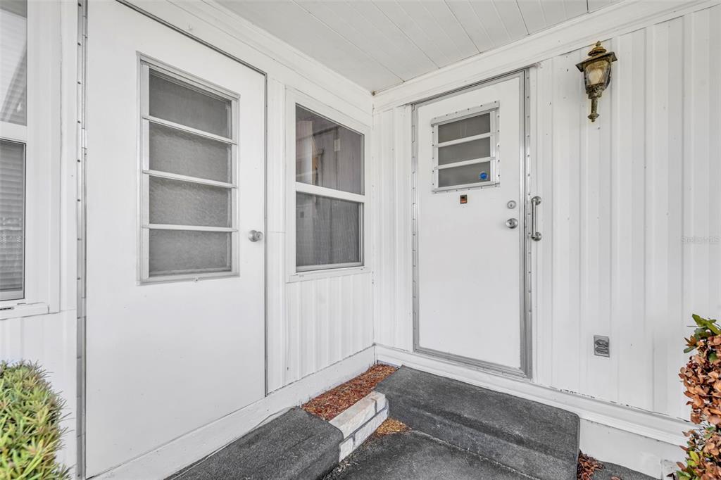 A white exterior wall features two doors with small windows and a wall-mounted light fixture — 270 PALAI AVENUE, LEESBURG, FL