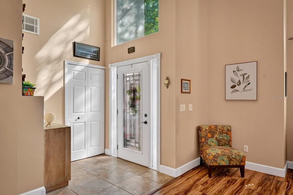An entryway features a white front door, tiled floor, high ceilings, and a patterned armchair — 4758 S PENINSULA DRIVE, PONCE INLET, FL