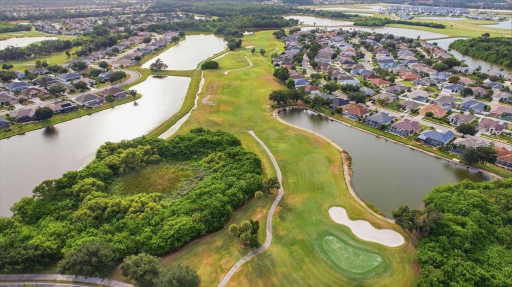 An aerial view shows a golf course fairway bordered by ponds and residential houses — 819 SPRINGWOOD CIRCLE, BRADENTON, FL