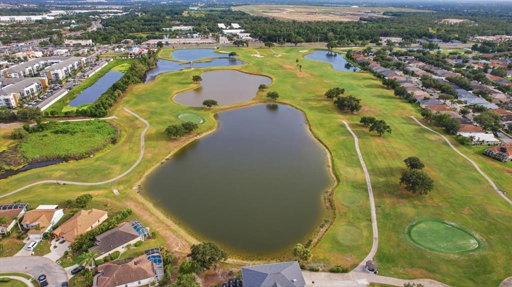 An aerial view shows a golf course fairway flanked by residential homes and multiple ponds — 819 SPRINGWOOD CIRCLE, BRADENTON, FL