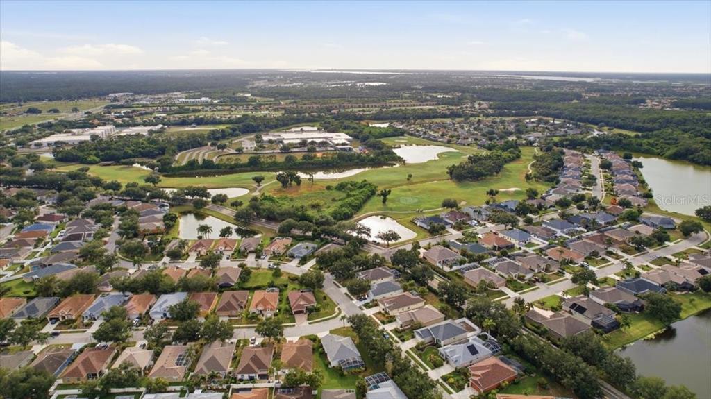 An aerial view shows a golf course with multiple ponds surrounded by residential houses — 819 SPRINGWOOD CIRCLE, BRADENTON, FL