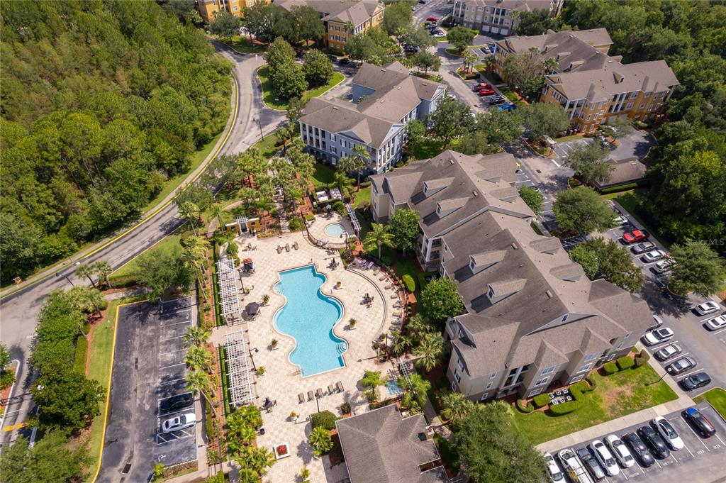Aerial view of an apartment complex featuring a swimming pool and surrounding parking lots — 3589 CONROY ROAD UNIT 1015, ORLANDO, FL