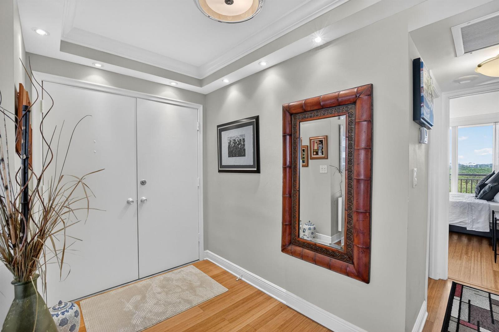 An entryway features light gray walls, hardwood floors, a double door, and a bamboo-framed mirror — 1180 S Ocean Boulevard # 0055, Boca Raton FL 33432, BOCA RATON, FL