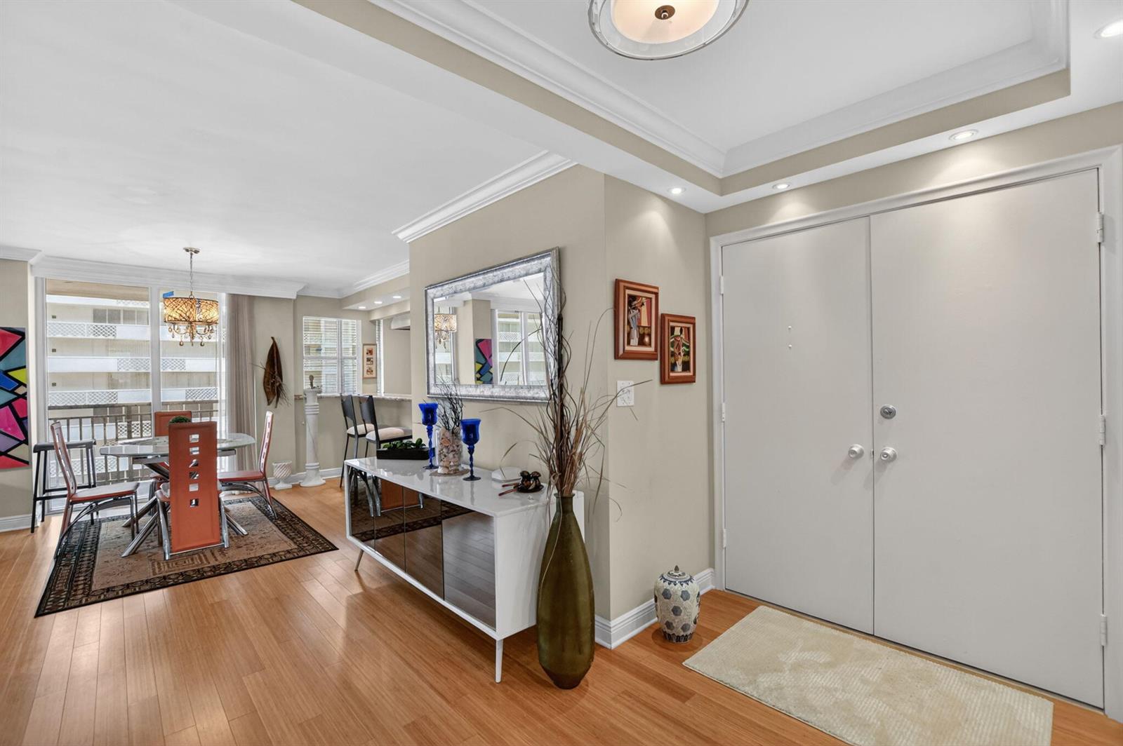 A dining area and entryway feature hardwood floors, a white sideboard, and a double door — 1180 S Ocean Boulevard # 0055, Boca Raton FL 33432, BOCA RATON, FL