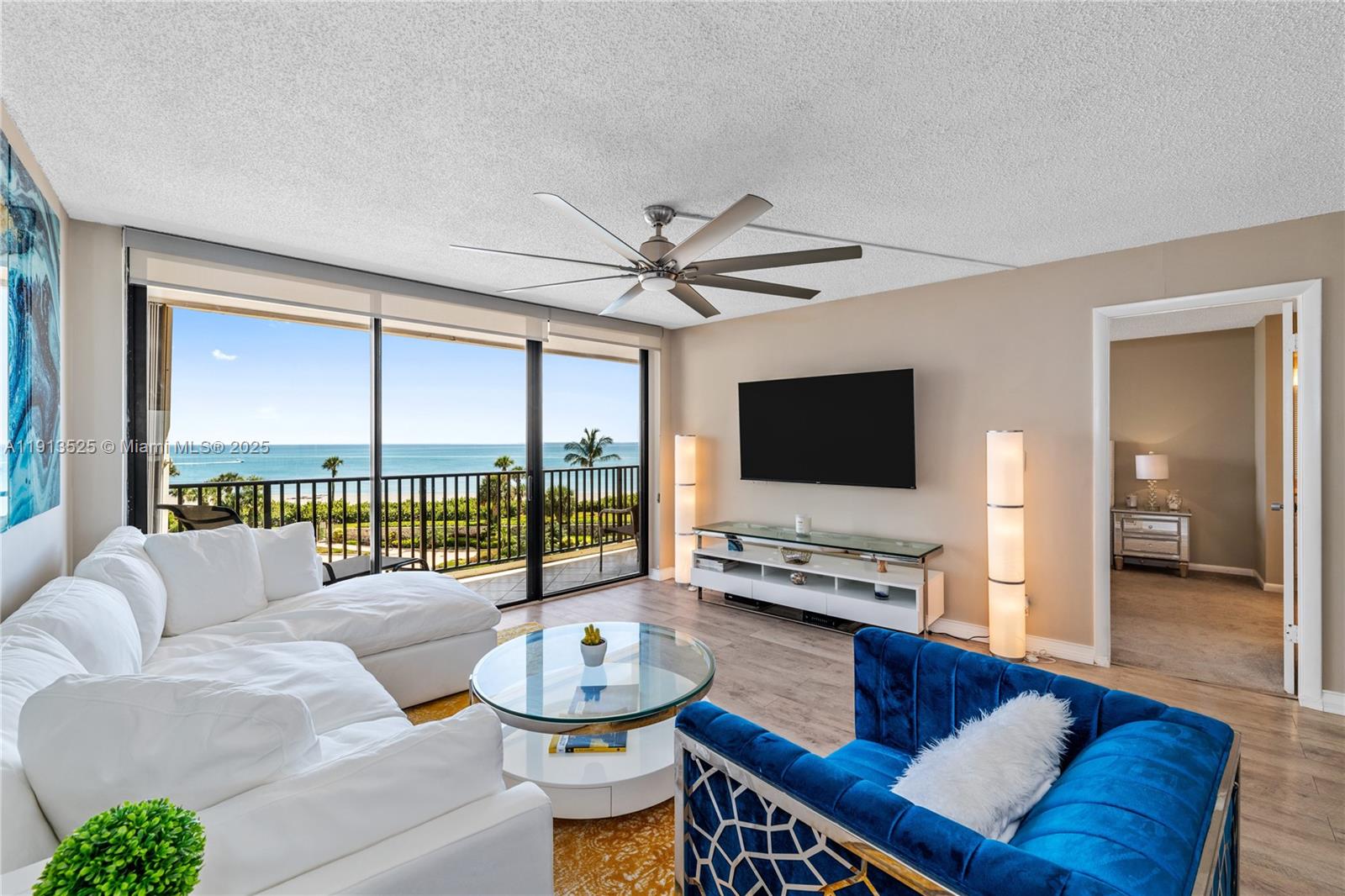 A living room features a white sectional, blue armchair, glass coffee table, and ocean view — 300 Ocean Trail Way # 406, Jupiter FL 33477, JUPITER, FL