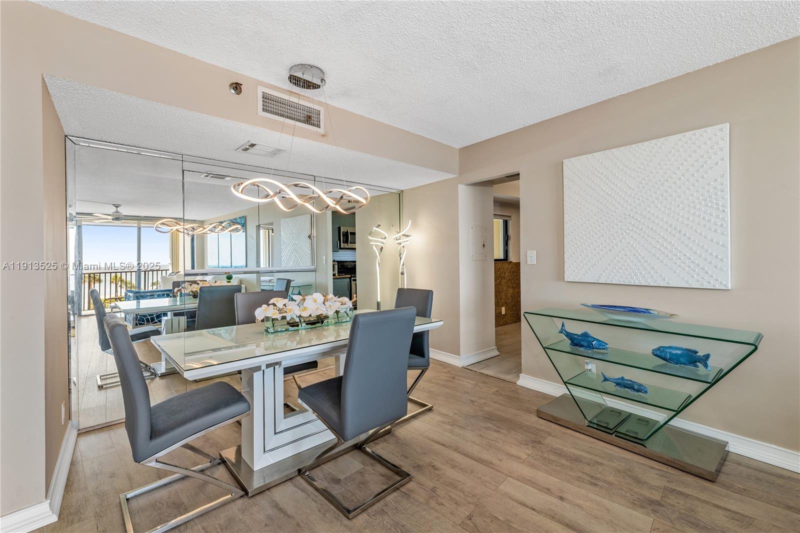 A dining room features a glass table, gray chairs, a mirrored wall, and wood flooring — 300 Ocean Trail Way # 406, Jupiter FL 33477, JUPITER, FL