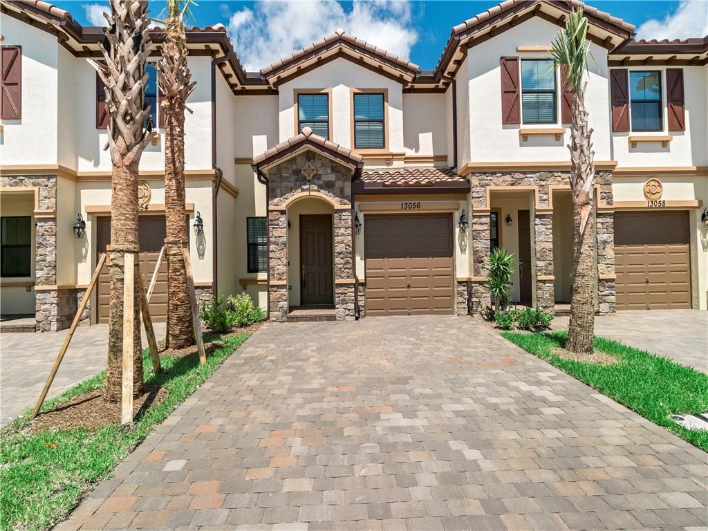 A row of three-story townhomes with stone accents, brown garage doors, and paved driveways — 13056 Anthorne Lane # 113, Boynton Beach FL 33436, BOYNTON BEACH, FL