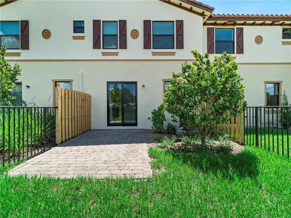The exterior of a two-story townhouse features a paved patio and a small fenced yard — 13056 Anthorne Lane # 113, Boynton Beach FL 33436, BOYNTON BEACH, FL