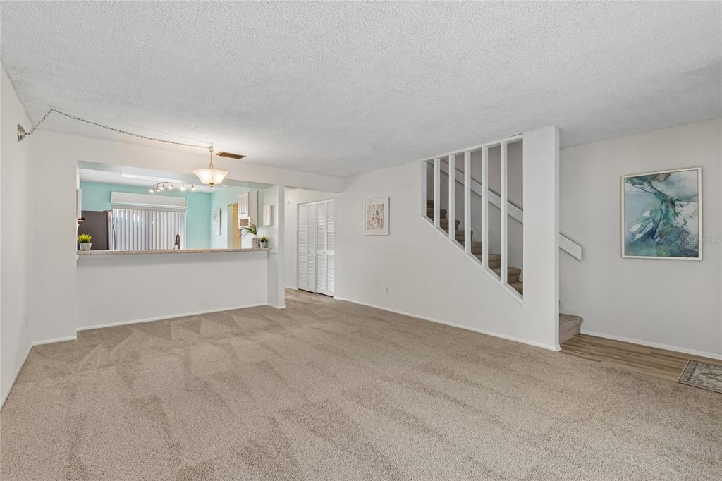 A carpeted living room features a breakfast bar, a staircase with white railings, and walls — 7803 AMBERLEA COURT, TEMPLE TERRACE, FL