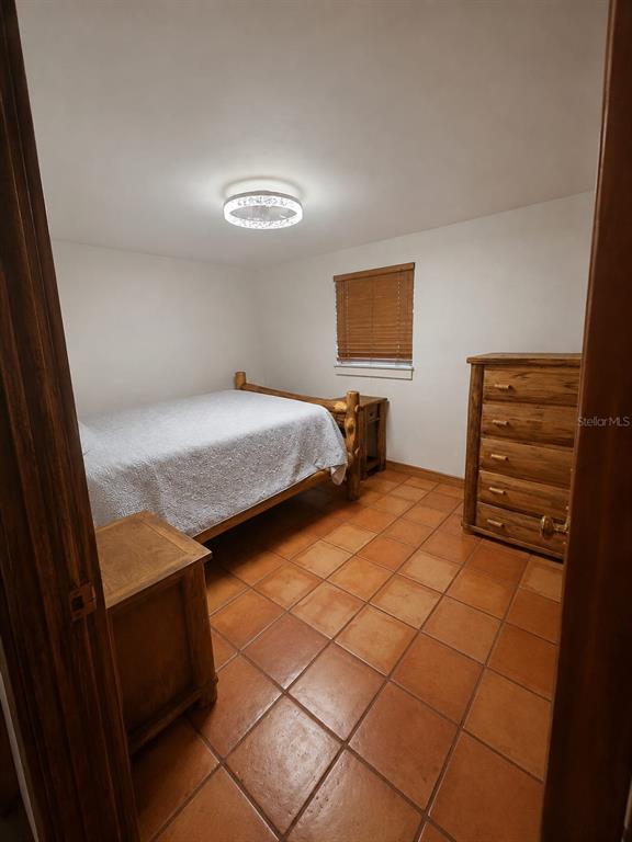 A bedroom with a wooden bed frame, a matching dresser, and terracotta tile flooring — 16109 INDIAN MOUND ROAD, TAMPA, FL