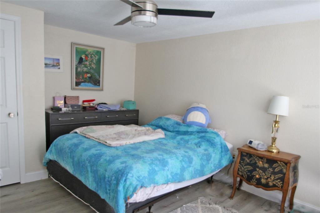 A bedroom features a bed with a blue comforter, a dresser, and a nightstand — 12217 SADDLE STRAP ROW, HUDSON, FL