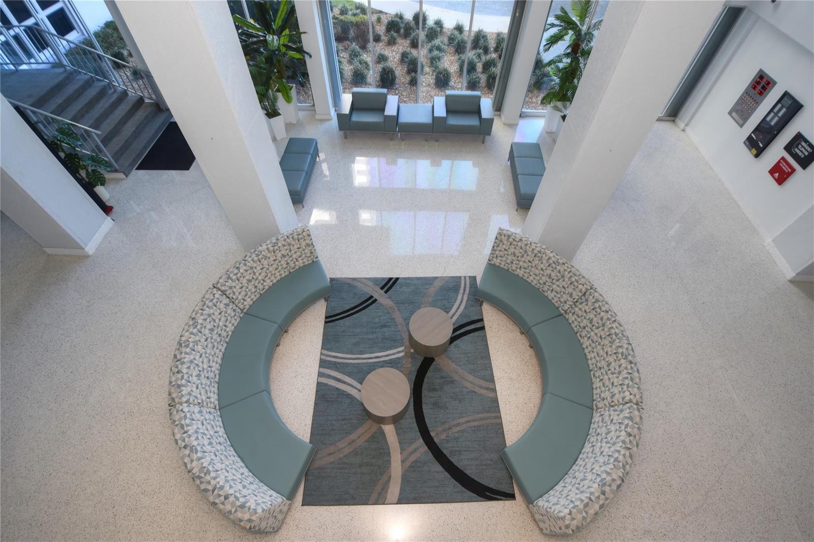An elevated view of a modern lobby featuring curved seating, a patterned rug, and stairs — 405 N Ocean Boulevard # 207, Pompano Beach FL 33062, POMPANO BEACH, FL