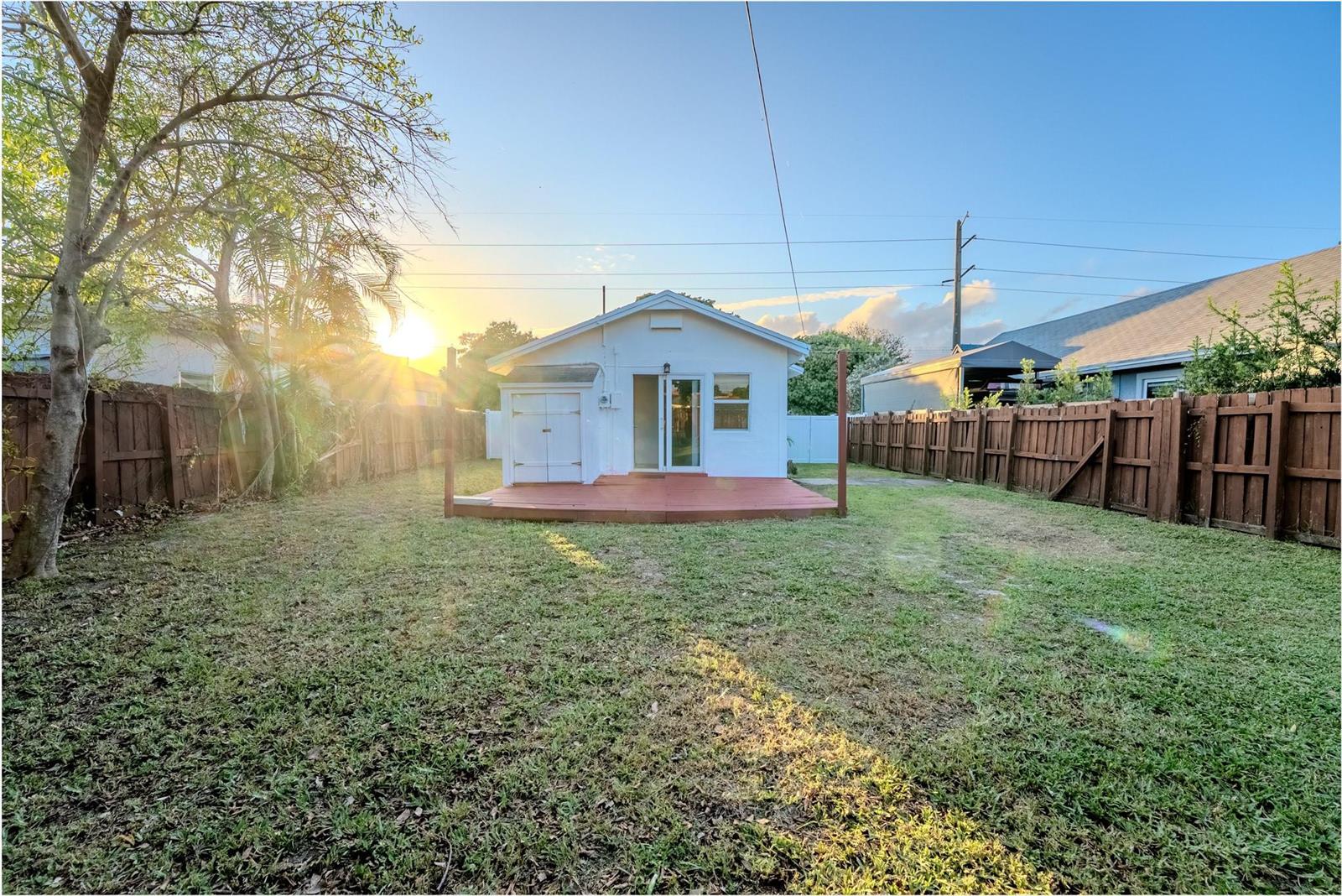 A small white house with a red deck stands in a fenced backyard at sunset — 521 S 24th Avenue, Hollywood FL 33020, HOLLYWOOD, FL