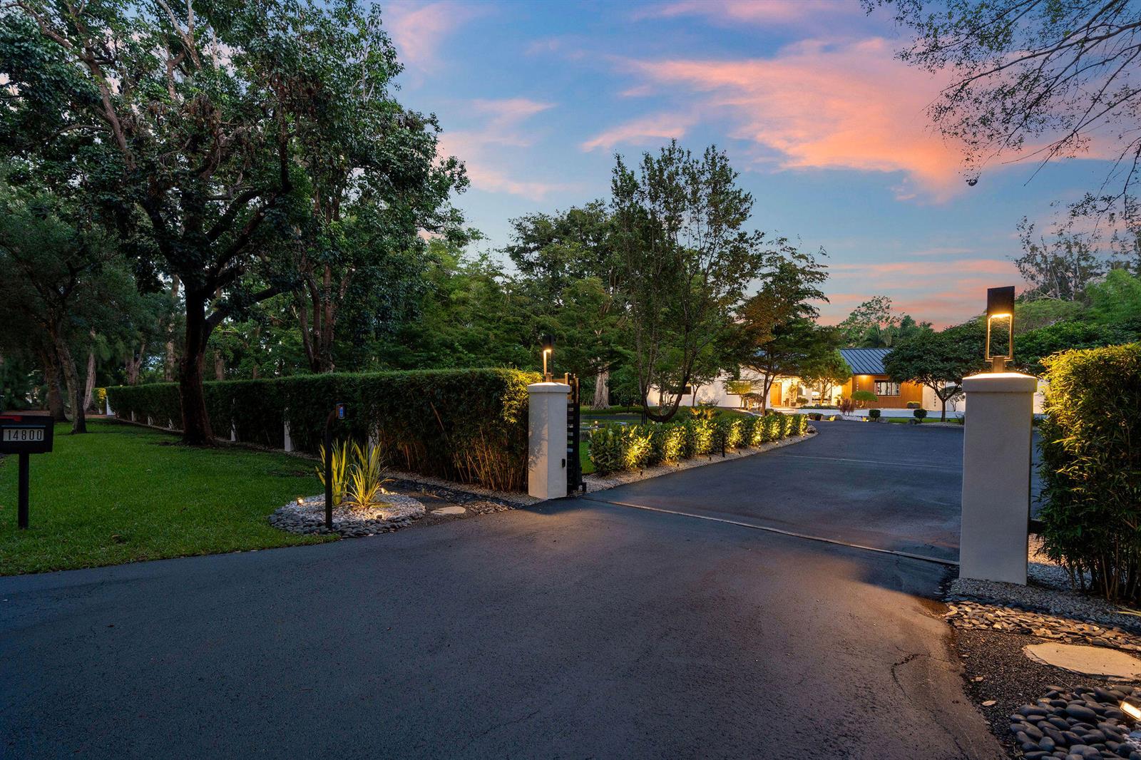 A paved driveway leads through a gated entrance toward a house surrounded by lush trees — 14800 Marvin Lane, Southwest Ranches FL 33330, SOUTHWEST RANCHES, FL