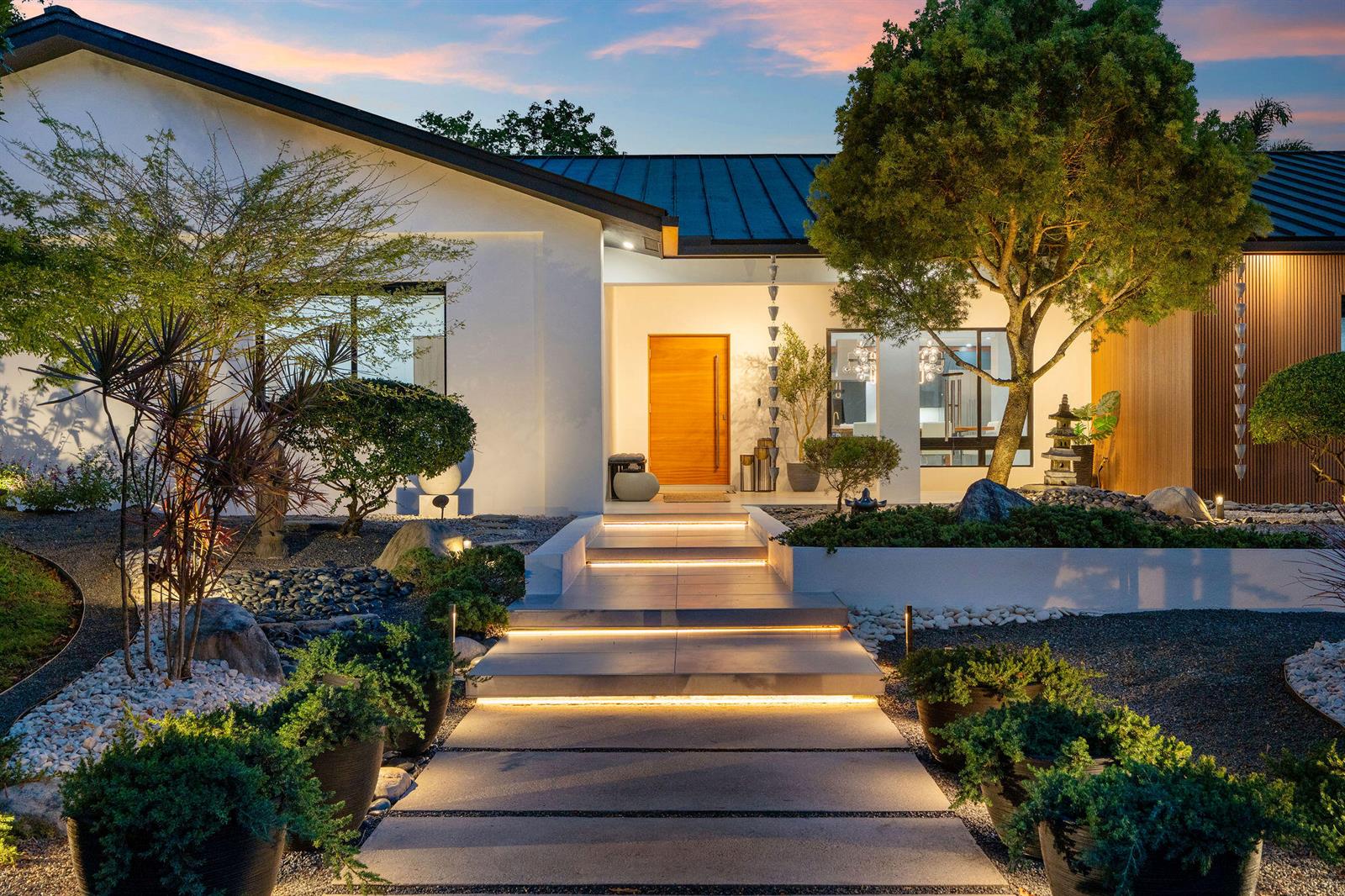 A modern house exterior features a stone walkway with integrated lighting leading to a wooden door — 14800 Marvin Lane, Southwest Ranches FL 33330, SOUTHWEST RANCHES, FL