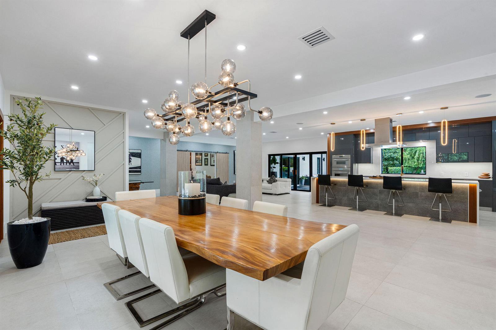A modern open-concept dining room and kitchen feature a live-edge table and globe chandelier — 14800 Marvin Lane, Southwest Ranches FL 33330, SOUTHWEST RANCHES, FL
