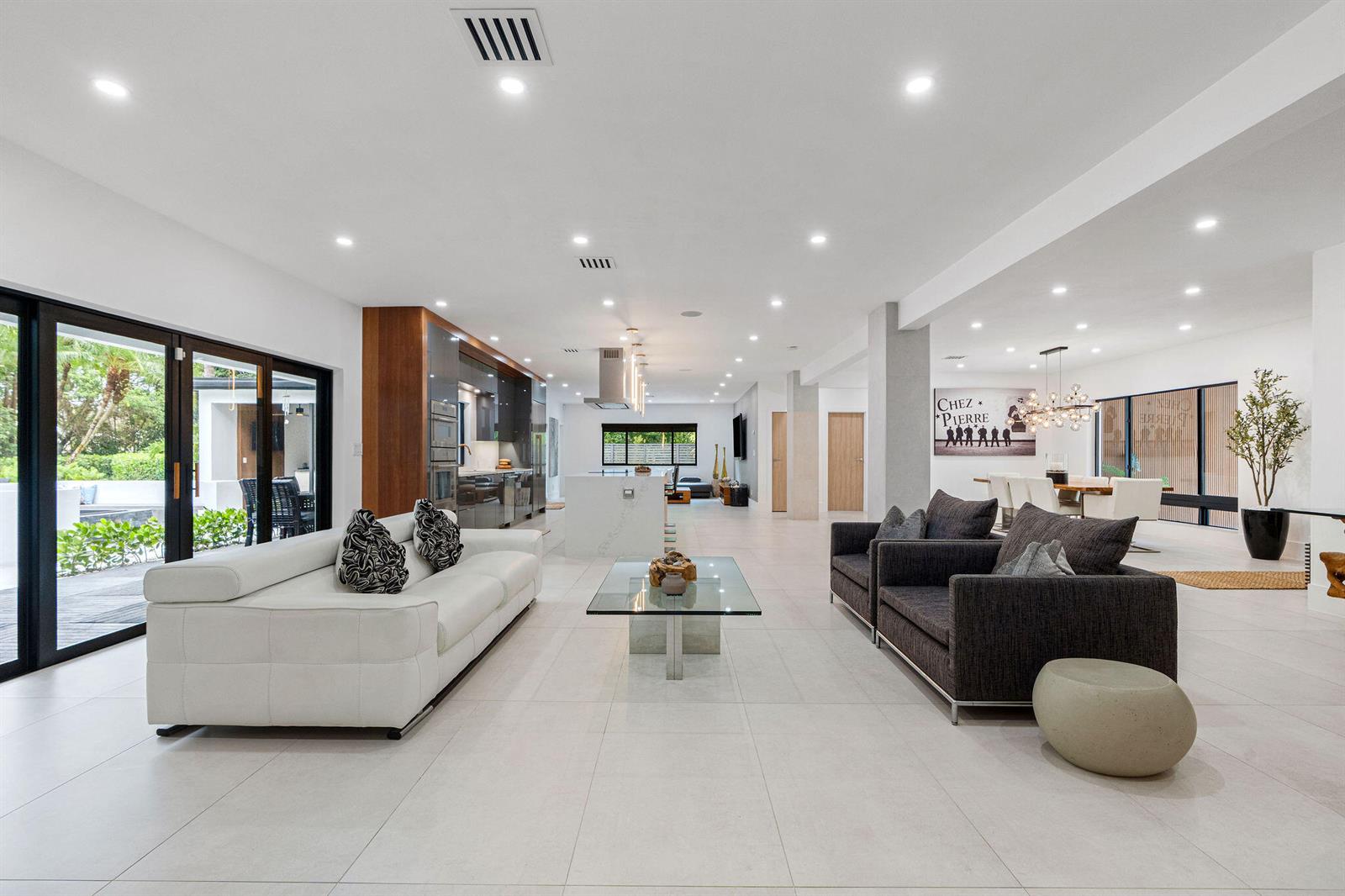A spacious open-concept living area features a white sofa, dark armchairs, and a modern kitchen — 14800 Marvin Lane, Southwest Ranches FL 33330, SOUTHWEST RANCHES, FL