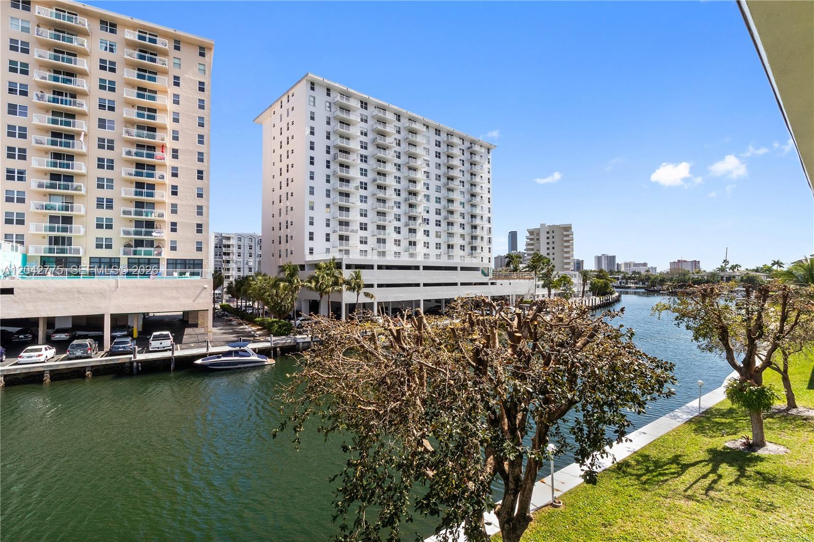 A view of a canal with two tall apartment buildings and a boat docked below — 450 Paradise Isle Blvd # 302, Hallandale Beach FL 33009, HALLANDALE BEACH, FL