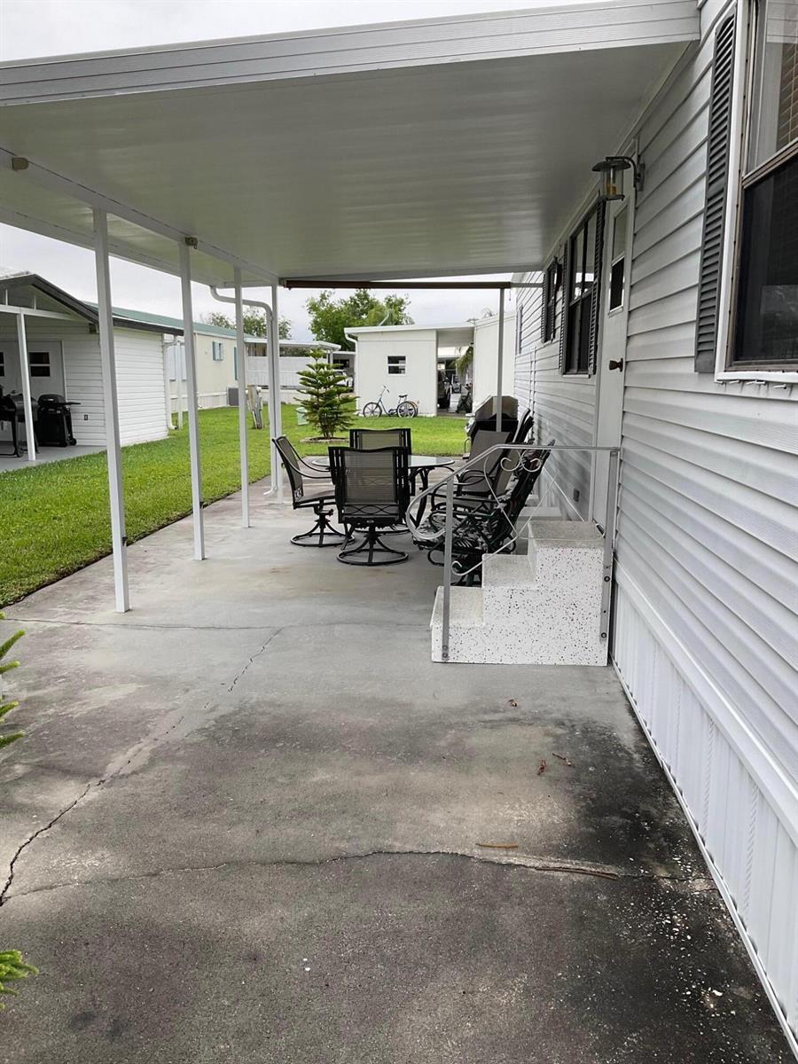 A covered concrete patio features outdoor furniture and steps leading to a white mobile home — 1601 Us, Okeechobee FL 34974, OKEECHOBEE, FL