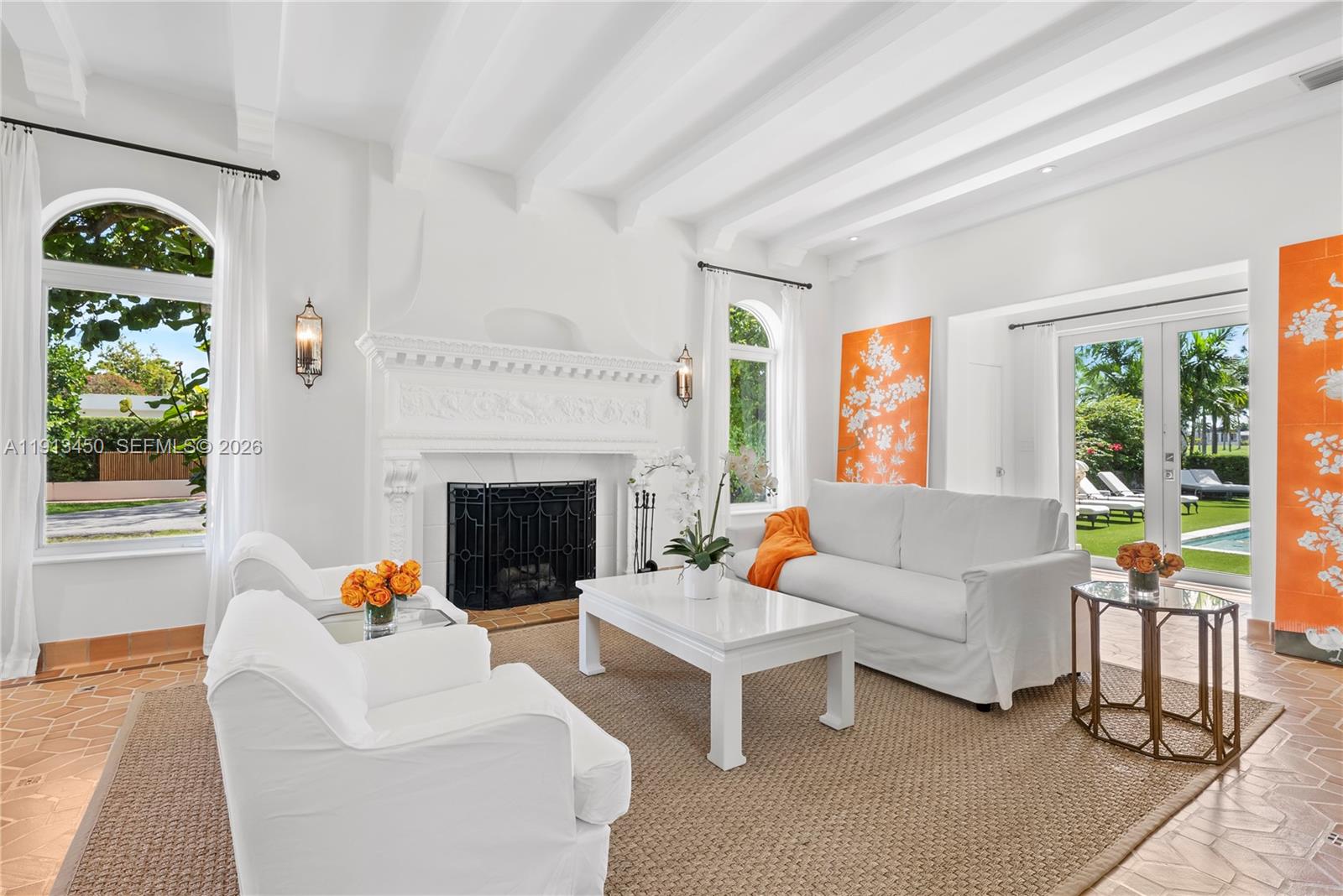 A bright living room features a white fireplace, vaulted beamed ceilings, and orange accent panels — 5800 La Gorce Dr, Miami Beach FL 33140, MIAMI BEACH, FL