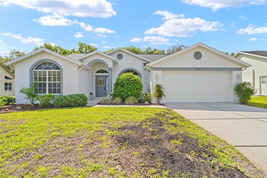 A single-story house with a white stucco exterior, a two-car garage, and a front lawn — 432 MISTWOOD COURT, SPRING HILL, FL
