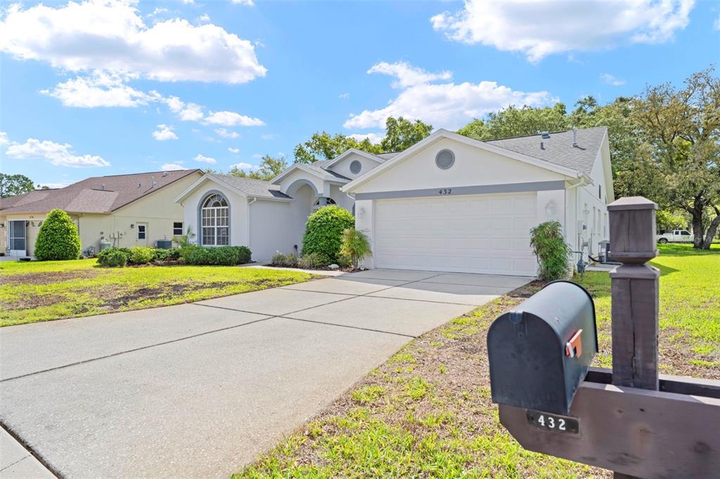 A single-story house with a white stucco exterior, a two-car garage, and a concrete driveway — 432 MISTWOOD COURT, SPRING HILL, FL