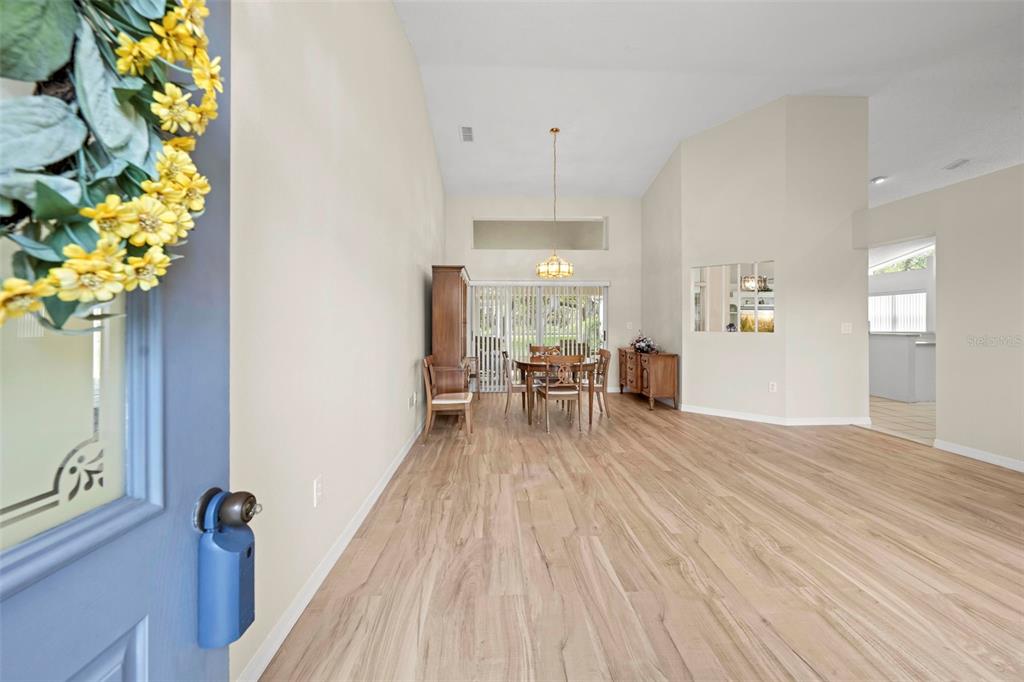 A dining area with wood-look flooring, a chandelier, and a sliding glass door — 432 MISTWOOD COURT, SPRING HILL, FL