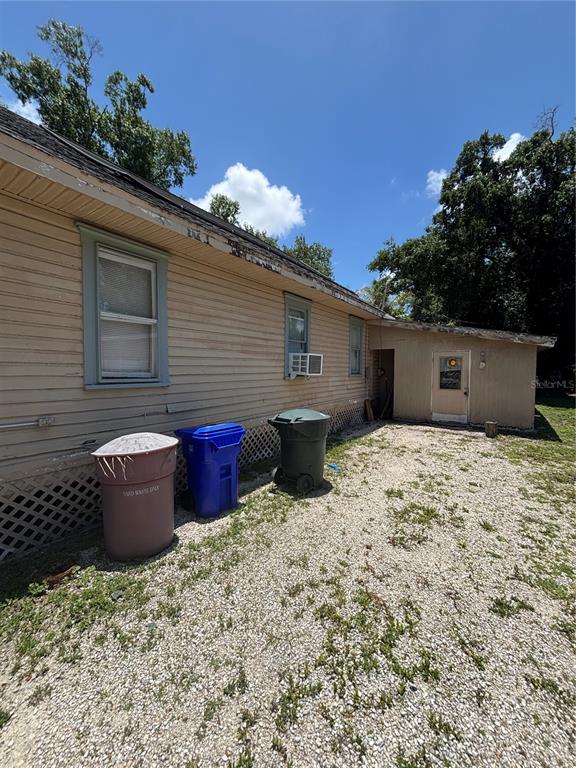 The exterior of a house with light-colored siding, three trash bins, and a gravel yard — 1906 HANSON STREET, FORT MYERS, FL