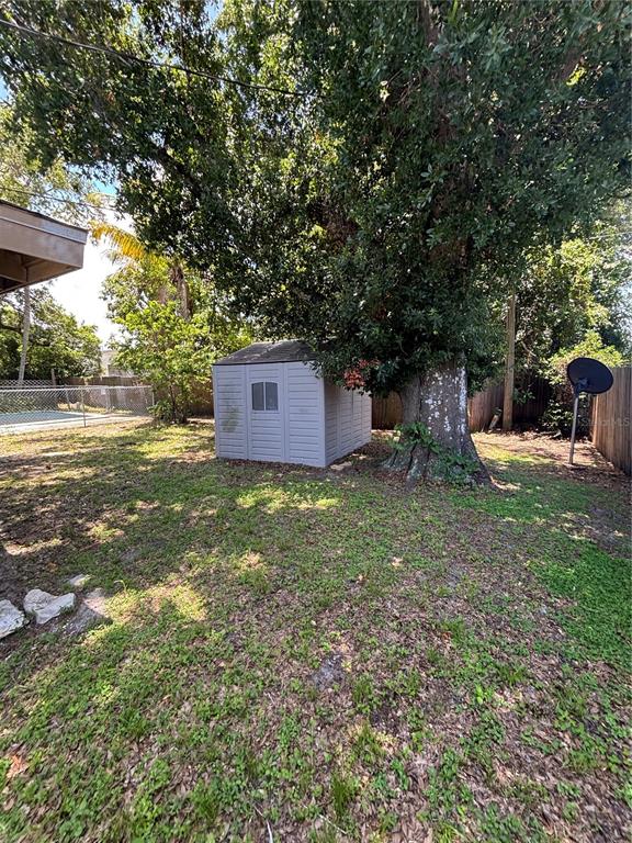 A gray plastic storage shed sits in a grassy backyard next to a large tree — 1906 HANSON STREET, FORT MYERS, FL