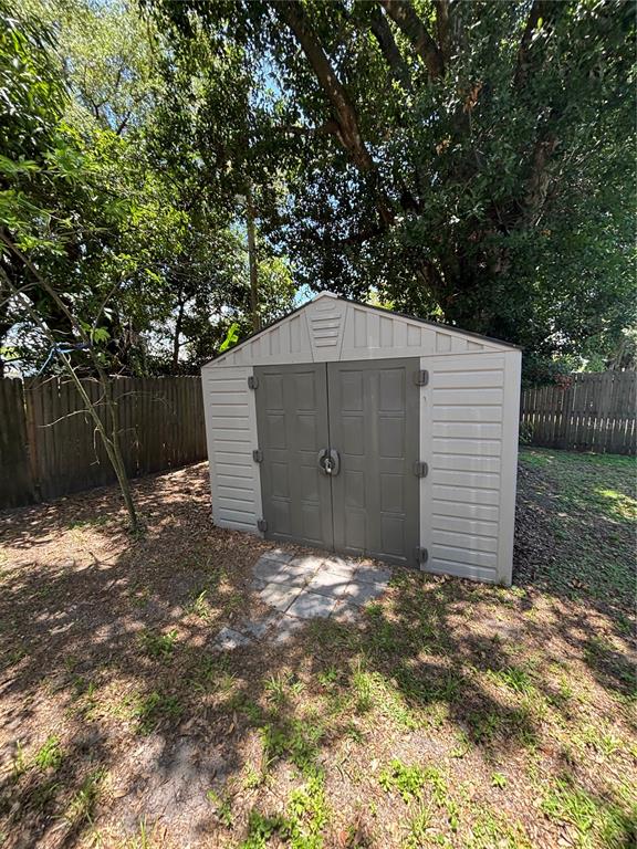 A beige and gray plastic storage shed sits in a backyard near a wooden fence — 1906 HANSON STREET, FORT MYERS, FL