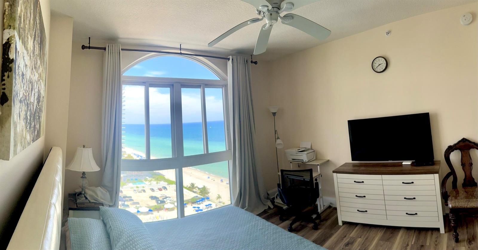 A bedroom features a bed, a dresser with a television, and a large arched window — 2080 S Ocean Drive, Hallandale Beach FL 33009, HALLANDALE BEACH, FL