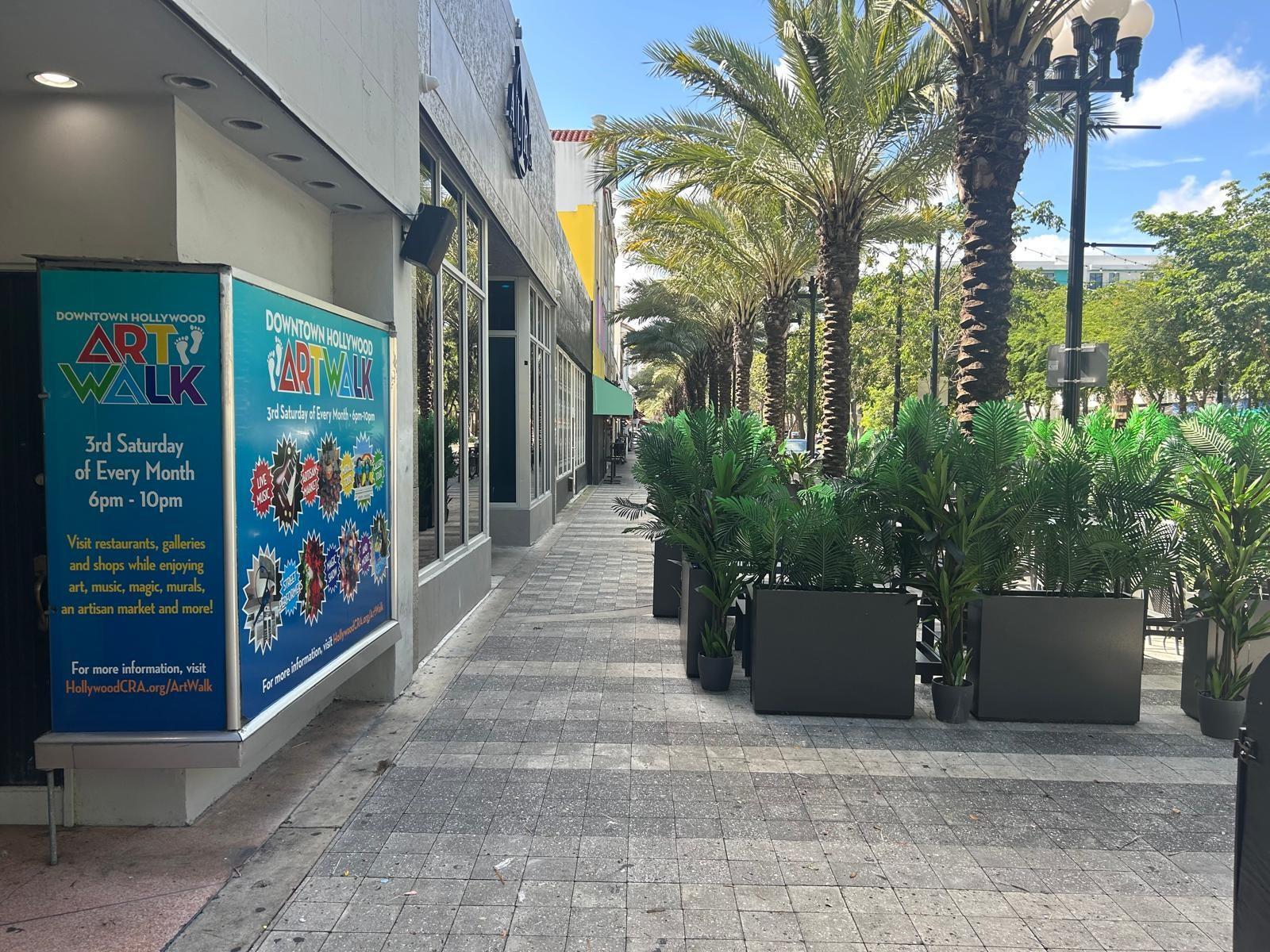 A sidewalk lined with potted palm plants and a sign for the Downtown Hollywood Artwalk — 1914 Hollywood Boulevard, Hollywood FL 33020, HOLLYWOOD, FL