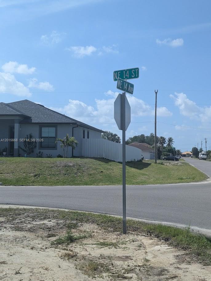 A street sign stands at the corner of a residential lot with a gray house — 1402 NE 14 ave, Cape Coral FL 33909, CAPE CORAL, FL
