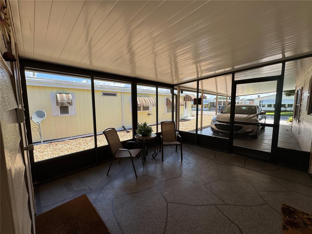 A screened-in porch with a patterned concrete floor, two chairs, and a small table — 6733 KENSINGTON DRIVE NE, WINTER HAVEN, FL