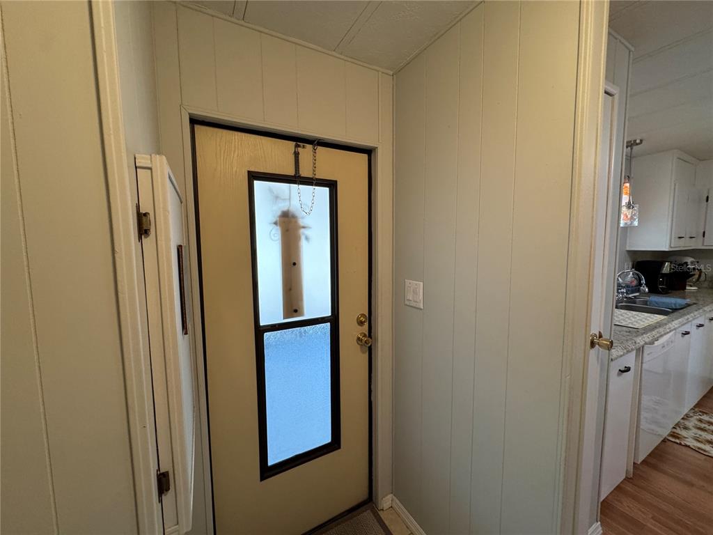 A light-colored entryway features a door with a vertical window and wood-paneled walls — 6733 KENSINGTON DRIVE NE, WINTER HAVEN, FL