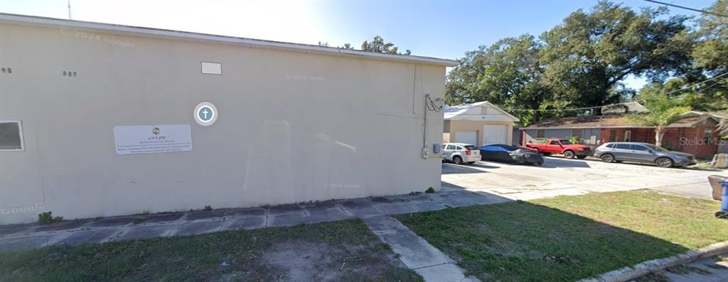 A beige exterior wall of a building with a sign and a parking lot nearby — 2806 N TAMPA STREET, TAMPA, FL