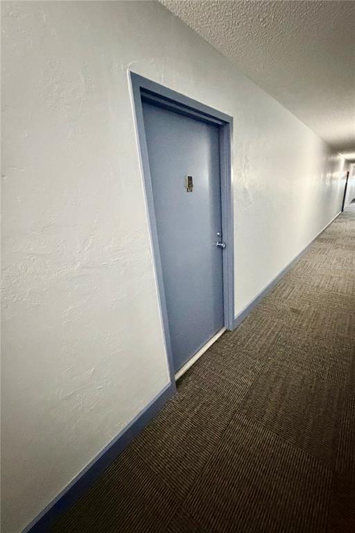 A blue door with a digital lock is situated in a long, carpeted apartment hallway — 2901 26TH STREET W UNIT 617, BRADENTON, FL