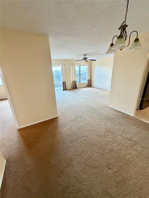 A carpeted living and dining area features a ceiling fan and sliding glass balcony doors — 2901 26TH STREET W UNIT 617, BRADENTON, FL
