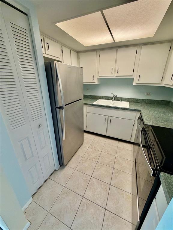 A kitchen features white cabinets, stainless steel appliances, and green countertops with tiled flooring — 2901 26TH STREET W UNIT 617, BRADENTON, FL
