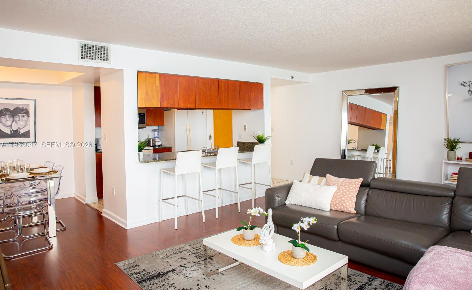 A living room features a dark leather sofa, a white coffee table, and a kitchen bar — 1200 Brickell Bay Dr # 1901, Miami FL 33131, MIAMI, FL