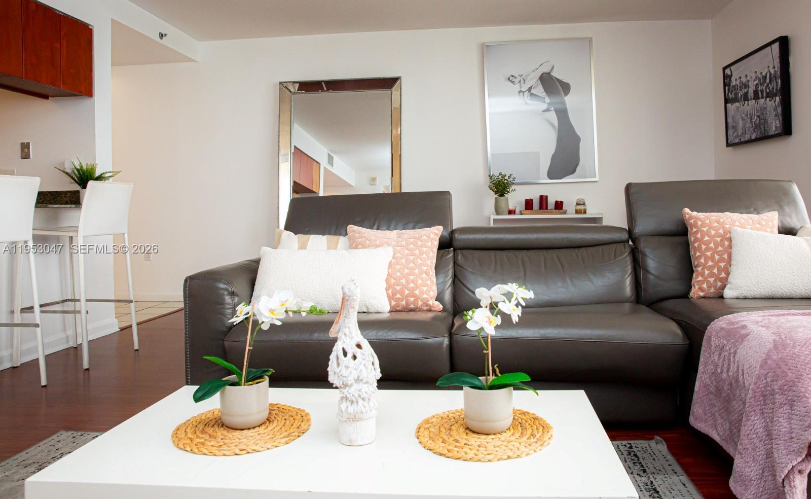 A living room features a dark leather sofa, a white coffee table, and wall art — 1200 Brickell Bay Dr # 1901, Miami FL 33131, MIAMI, FL