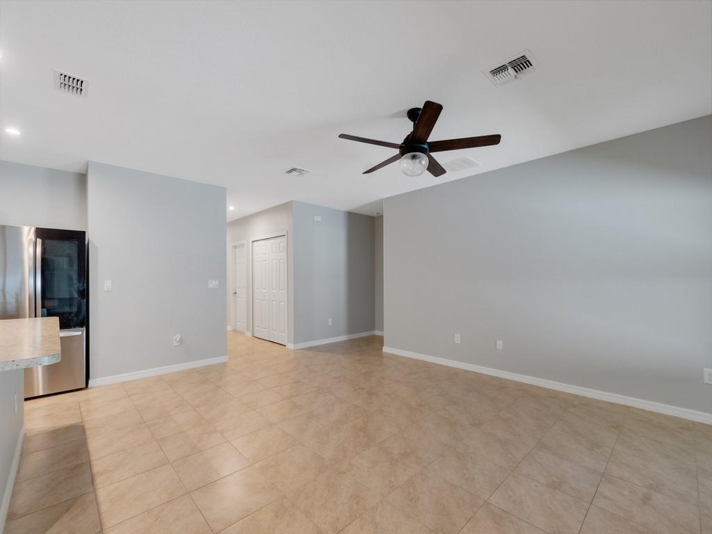 An empty room with light gray walls, tile flooring, and a dark ceiling fan — FORT PIERCE, FL