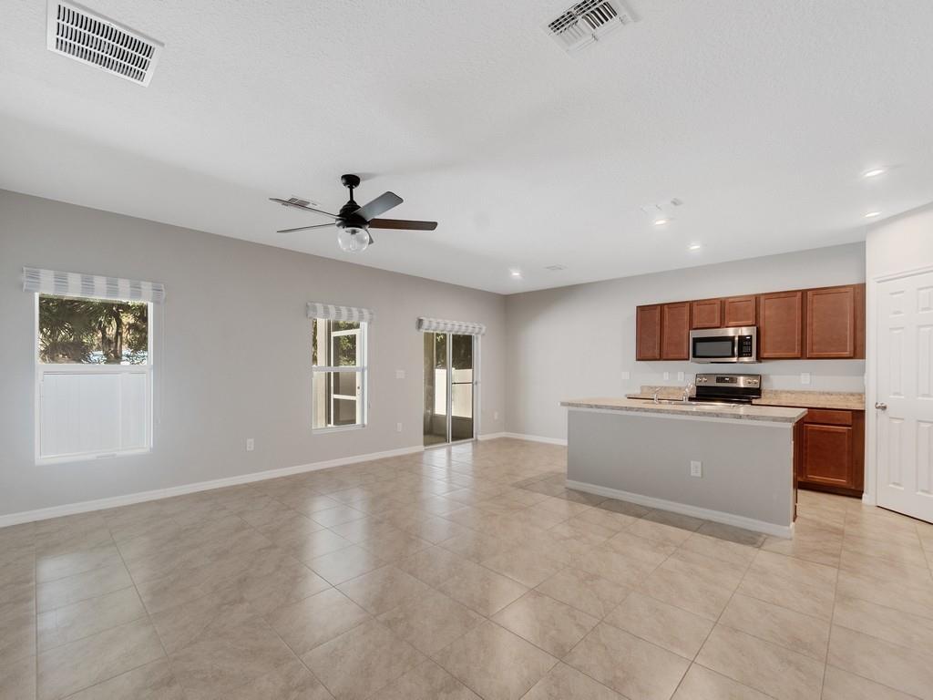 An open-concept kitchen and living area features tile flooring, wood cabinets, and sliding glass doors — FORT PIERCE, FL