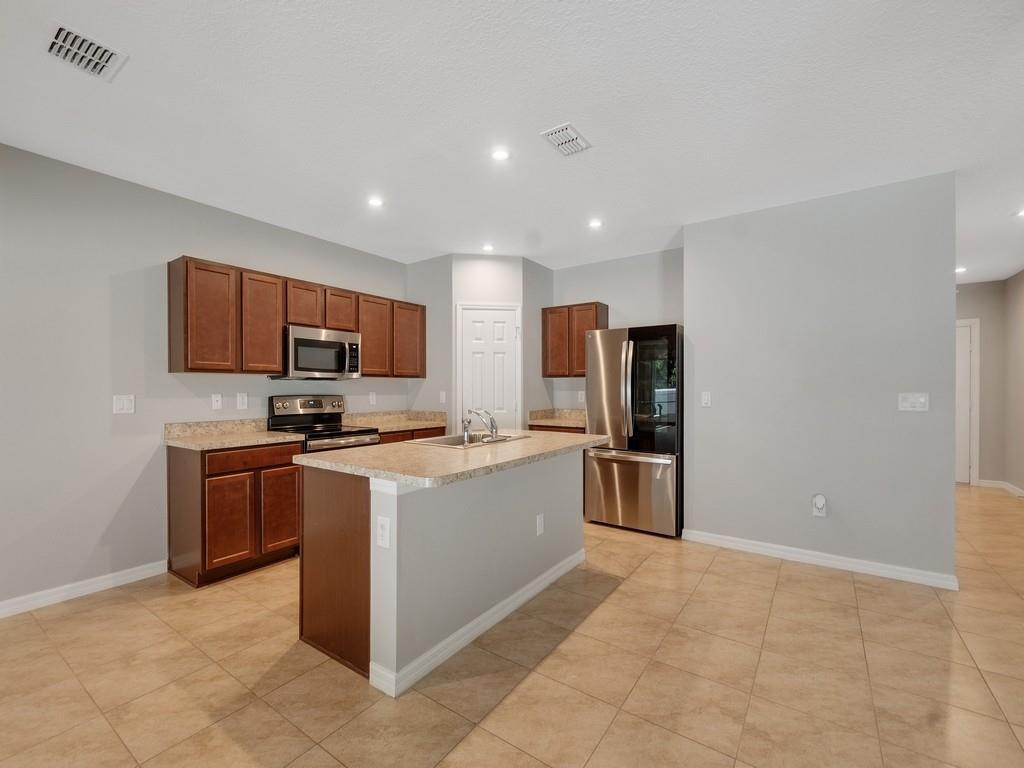 A kitchen features dark wood cabinets, stainless steel appliances, a center island, and tile flooring — FORT PIERCE, FL